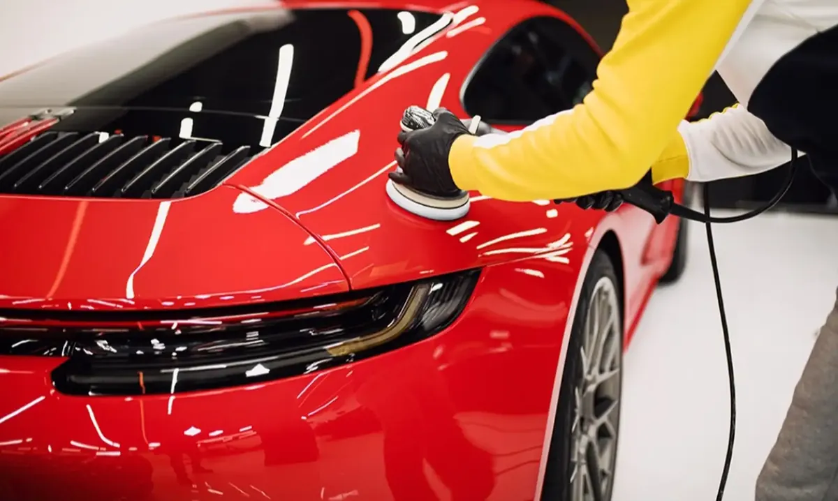Detailer machine polishing the rear fender of a red sports car